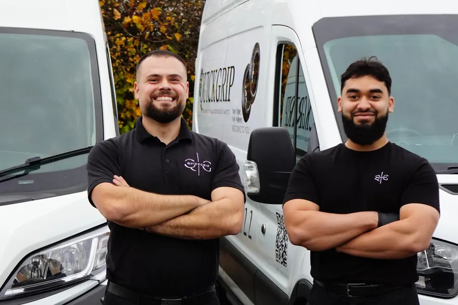 QuickGrip team standing in front of two branded vans
