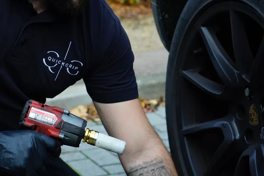 QuickGrip technician using an impact wrench on a Porsche wheel