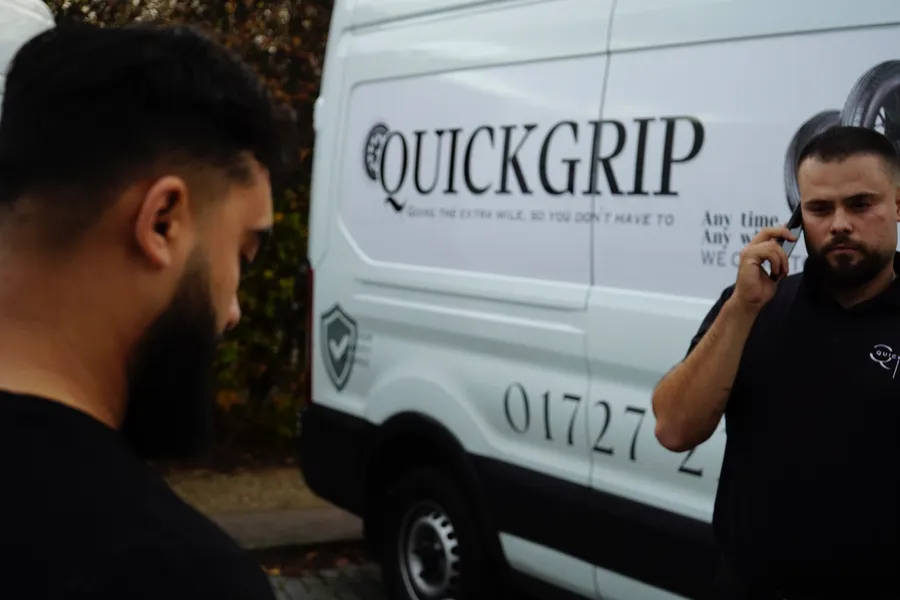 QuickGrip technician on the phone, branded van in the background